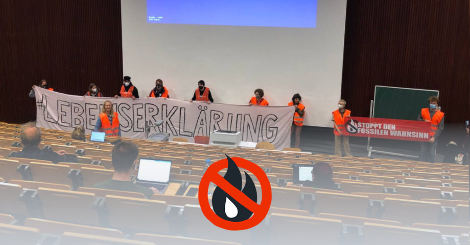 Besetzter Hörsaal mit Logo der Letzten Generation im Vordergrund