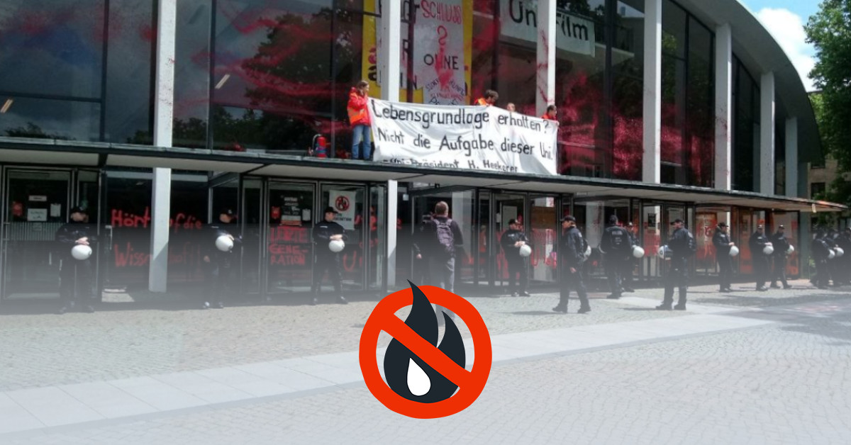 The orange-red colored auditorium is surrounded by police. People hold up a banner on the entrance canopy with the inscription "Preserve livelihoods? Not the task of this university. - University President H. Heekeren".