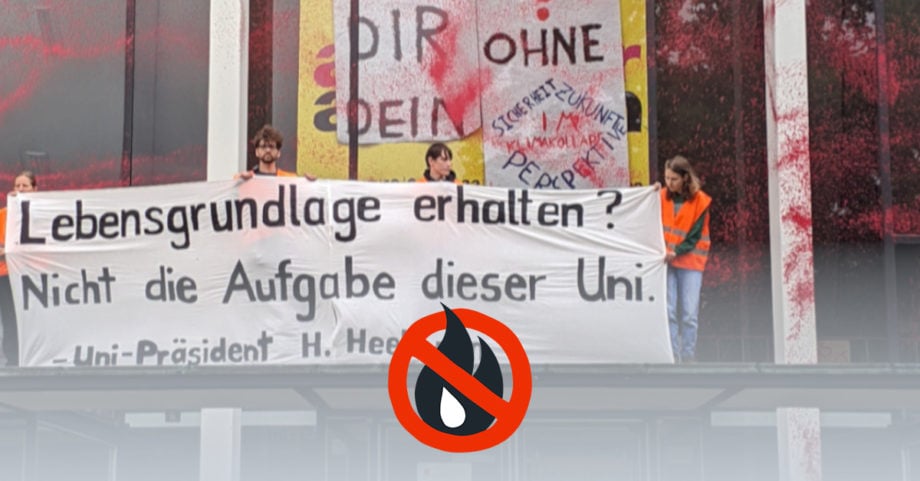 Menschen halten ein Banner mit der Aufschrift "Lebensgrundlage erhalten? Nicht die Aufgabe dieser Uni. - Uni-PrÀsident H. Heekeren". Das GebÀude hinter ihnen ist mit rot-oranger Farbe gefÀrbt.