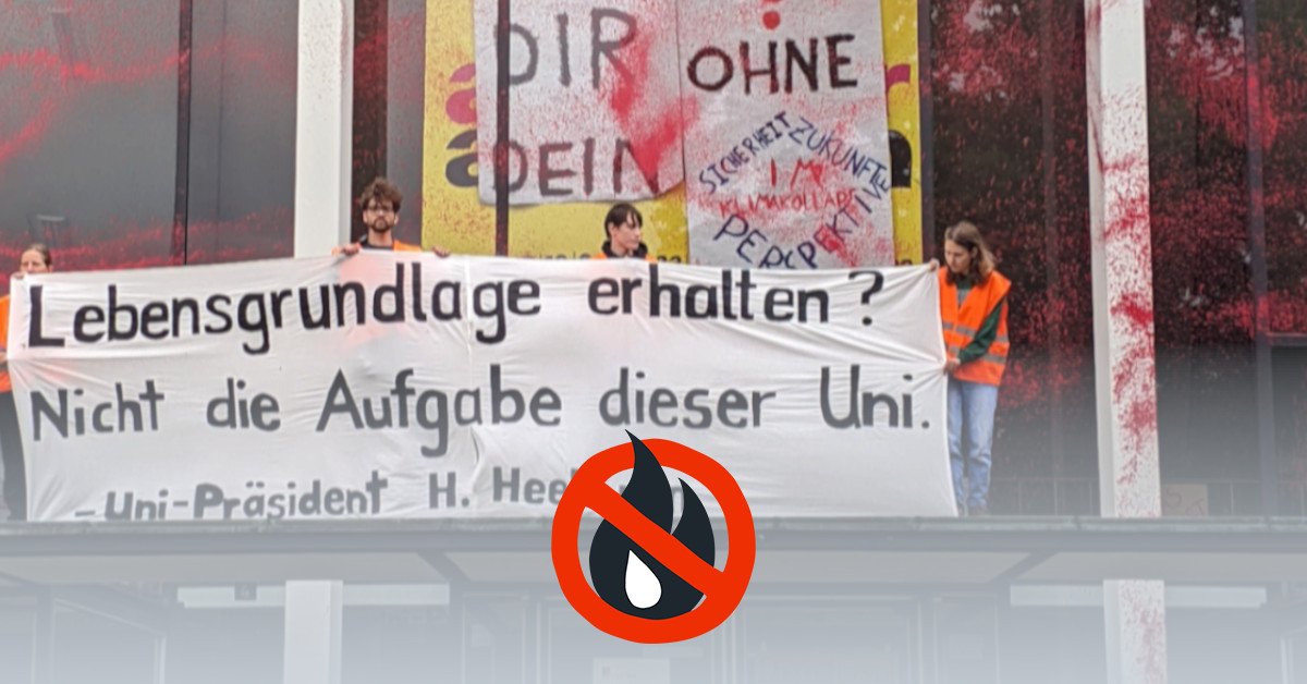 Menschen halten ein Banner mit der Aufschrift "Lebensgrundlage erhalten? Nicht die Aufgabe dieser Uni. - Uni-Präsident H. Heekeren". Das Gebäude hinter ihnen ist mit rot-oranger Farbe gefärbt.