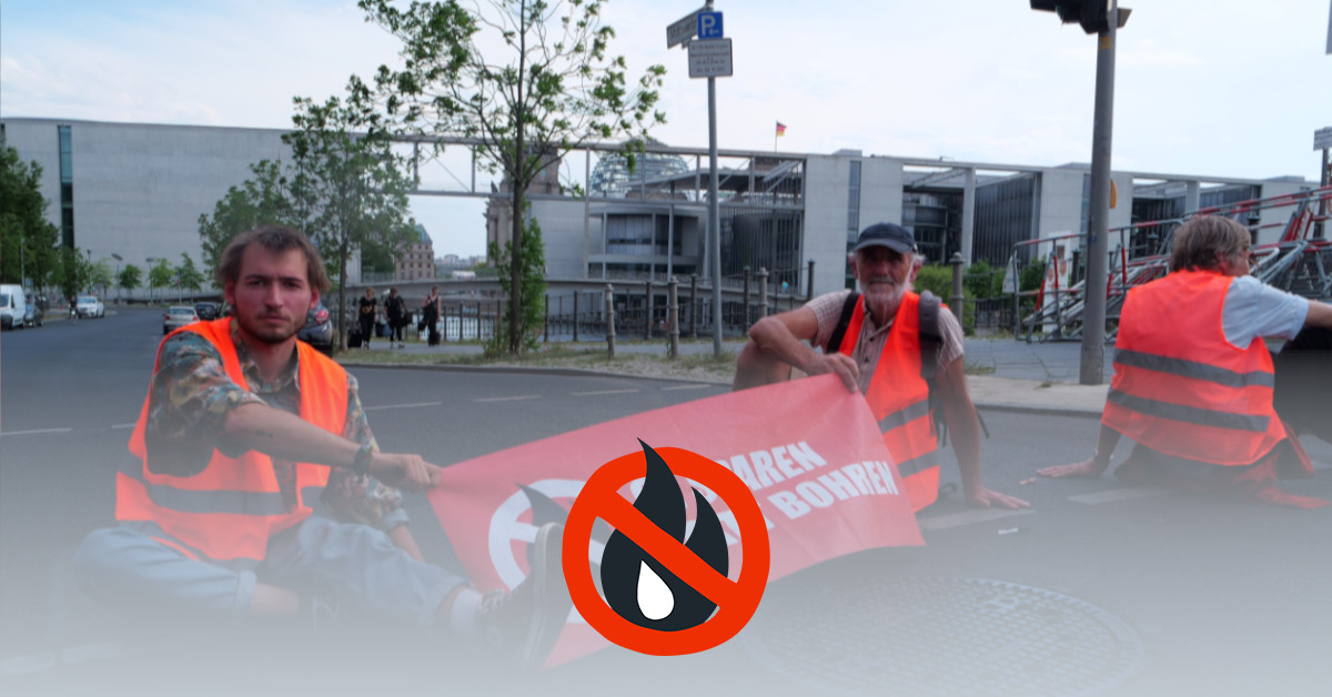 Three people are sitting on the street wearing high-visibility vests. They hold a banner that says "Save oil instead of drilling." The Bundestag can be seen in the background.