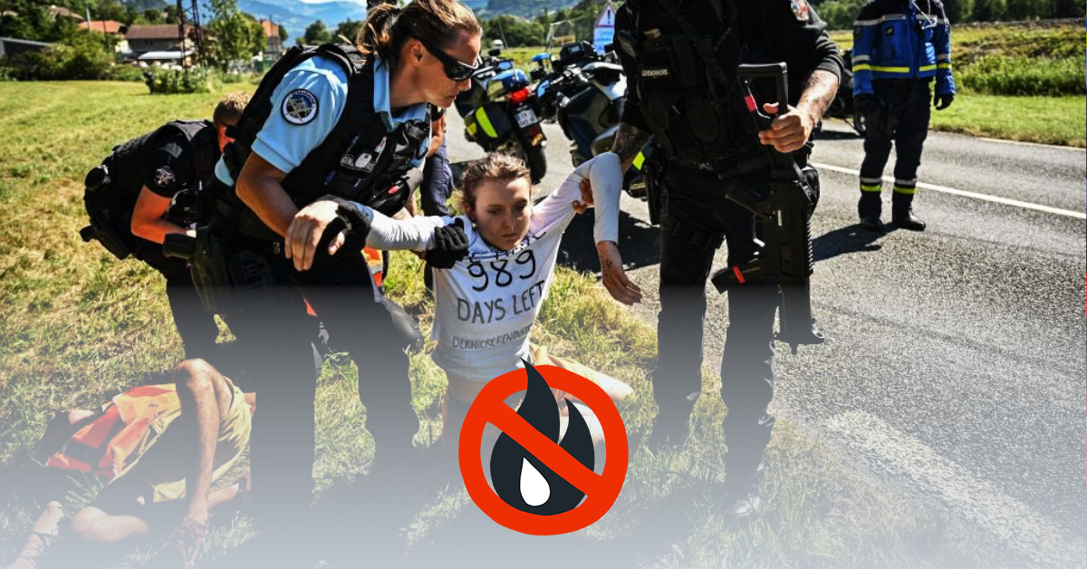 A person gets pulled away from a street by the police. She wears a shirt on which is written "We have 989 days left" and "dernierrenovation.fr".