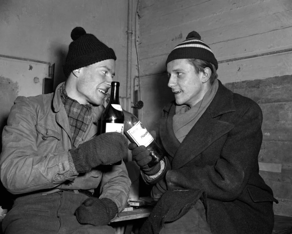 René Leudesdorff (left) and Georg von Hatzfeld toast each other with a bottle of wine in the anti-aircraft bunker on the island of Helgoland. In December 1950, the two Heidelberg students, accompanied by two journalists, crossed over to British-occupied Heligoland. They raise several flags there. | © Source: picture alliance / dpa